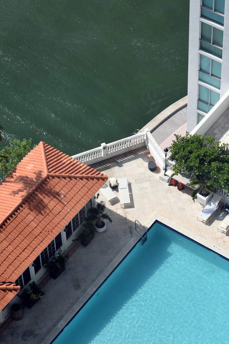 Aerial shot of a modern apartment with swimming pool near waterfront, bright and inviting.