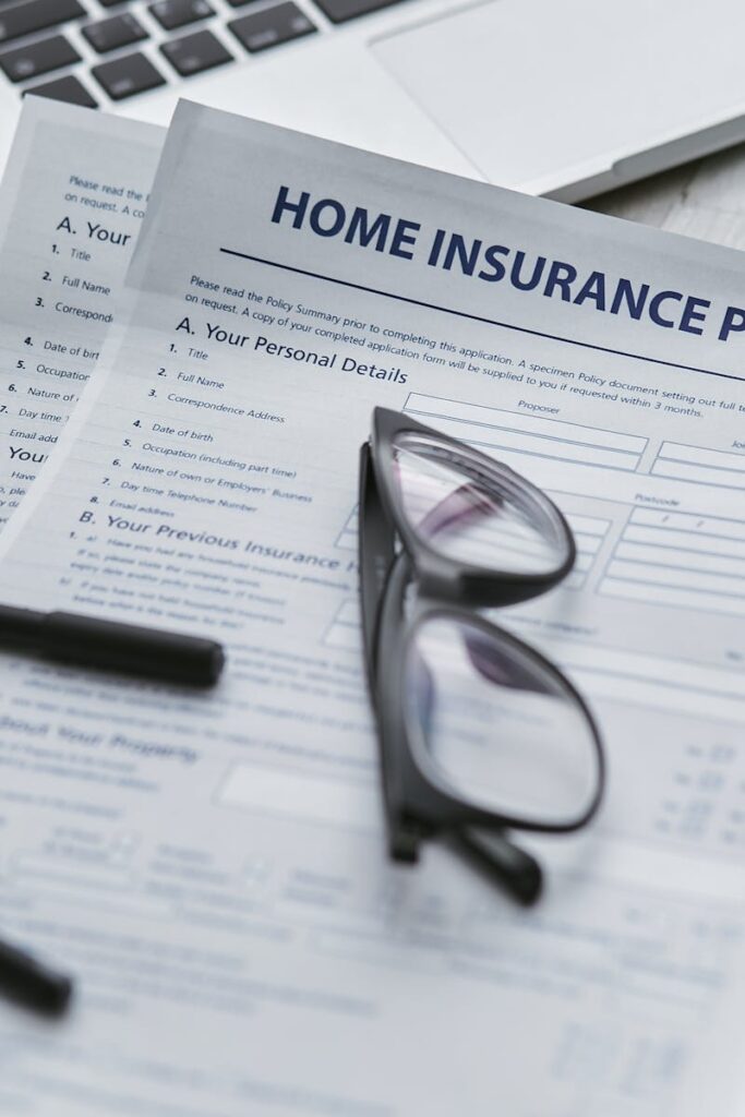 Close-up of home insurance policy document with glasses and laptop on a table.